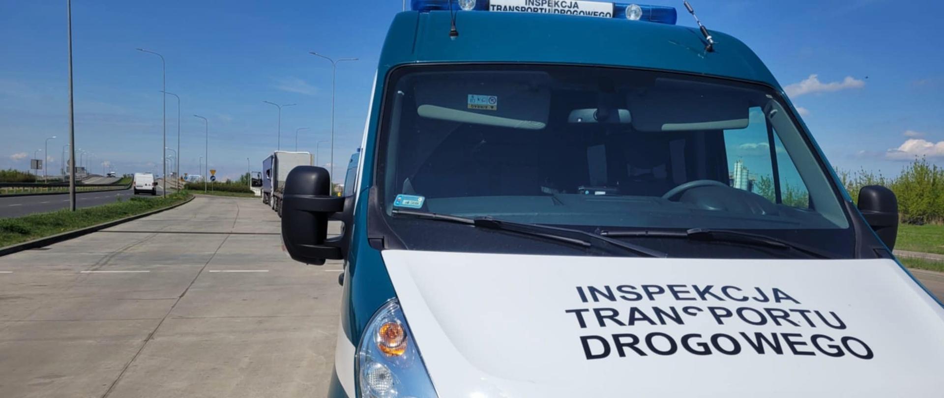 Na pierwszym planie: przód oznakowanego furgonu mazowieckiej Inspekcji Transportu Drogowego. W tle: dwa kontrolowane ciągniki siodłowe z podpiętymi naczepami.
