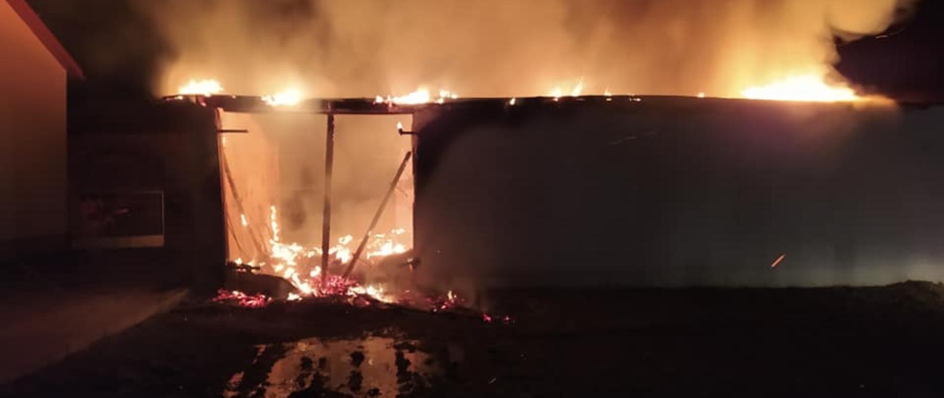 Zdjęcie zostało wykonane nocą, widać na nim płonący budynek, jest dużo ognia i szarego dymu