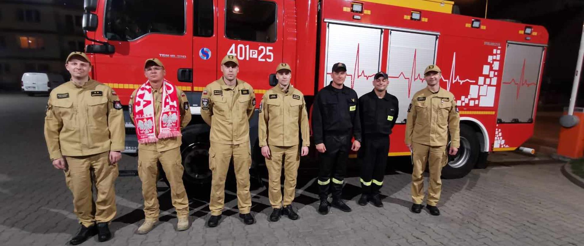 Zdjęcie przedstawia strażaków, którzy zostali wysłani aby gasić pożary w Grecji.
W tle pojazdy gaśnicze i budynek Komendy.
