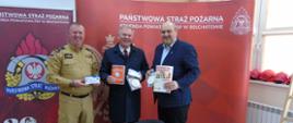 na zdjęciu komendant oraz zaproszeni goście promujący czujki dymu i czadu w tle loga straży pożarnej