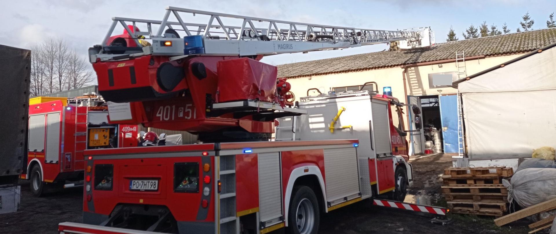 Zdjęcie przedstawia strażaków gaszących pożar w zakładzie tapicerskim w miejscowości Milcz.
W tle budynki.
