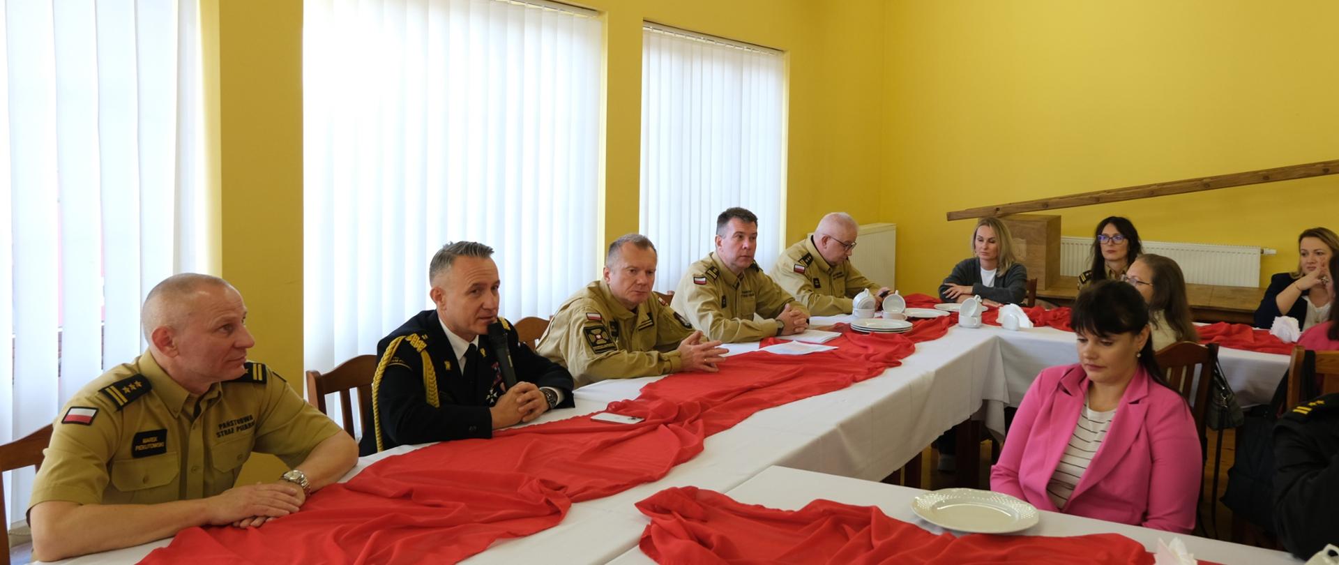 komendant główny PSP podczas przemówienia siedzący przy stole wraz z dyrektorami KG PSP 