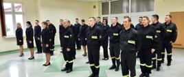 Na zdjęciu widoczni kursantki oraz kursanci szkolenia podstawowego w zawodzie strażak, w ubraniach koszarowych oraz służbowych.