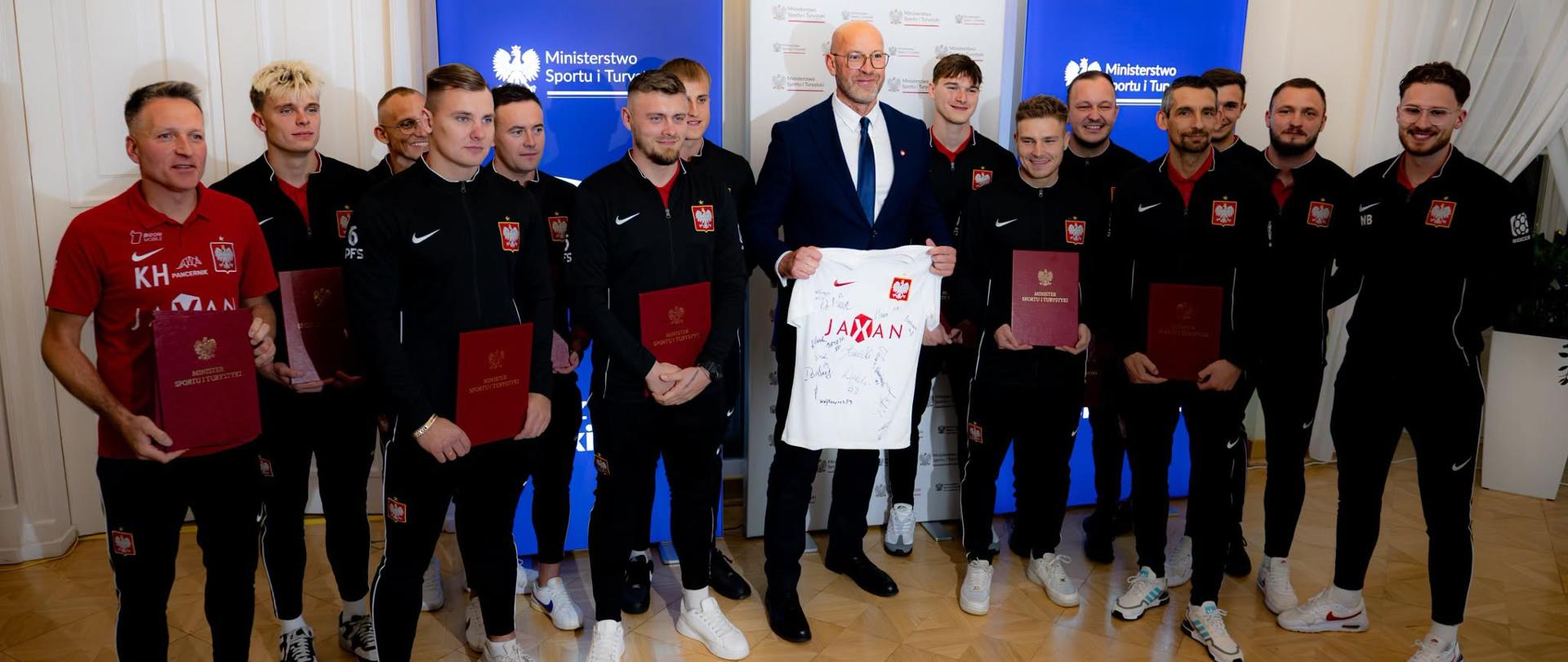 Zdjęcie zbiorowe uczestników spotkania w MSiT, w którym uczestniczyli minister sportu i turystyki Jakub Rutnicki i przedstawiciele Polskiej Federacji Socca oraz zawodnicy męskiej reprezentacji Polski.