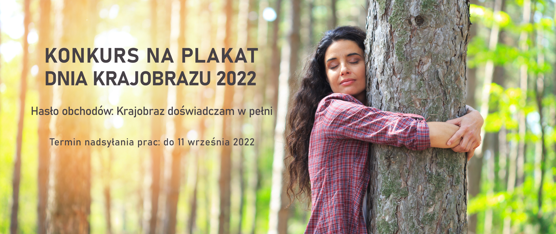 W tle la. Na pierwszym planie kobieta z długimi włosami i w kolorowej koszuli przytula się do drzewa. Ma zamknięte oczy. Po lewej stronie napis: Konkurs na plakat Dnia Krajobrazu 2022. Hasło obchodów: Krajobraz doświadczam w pełni. Termin nadsyłania prac: do 11 września 2022 