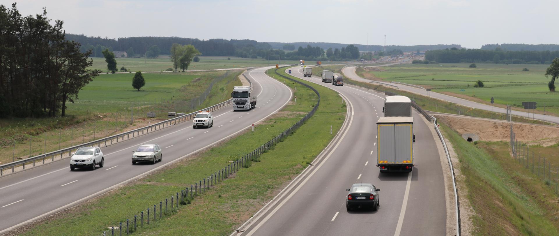 Dwie jezdnie na drodze ekspresowej, na każdej po kilka różnych pojazdów 