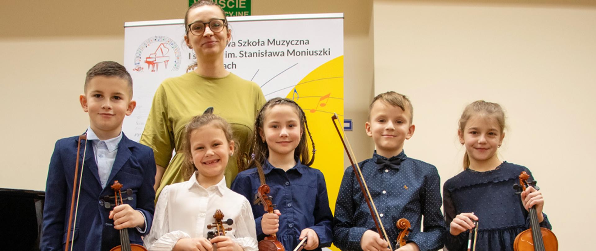 Na zdjęciu pięcioro uczniów wraz z nauczycielką, w tle baner szkoły.