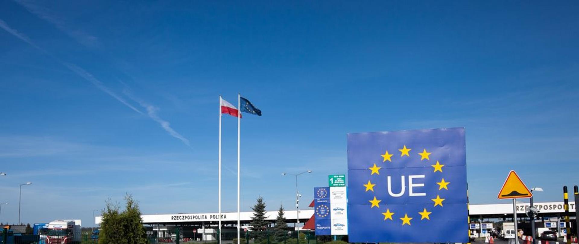 Przejście graniczne z widocznym znakiem Unii Europejskiej, flagami Polski i UE oraz pasami odpraw.