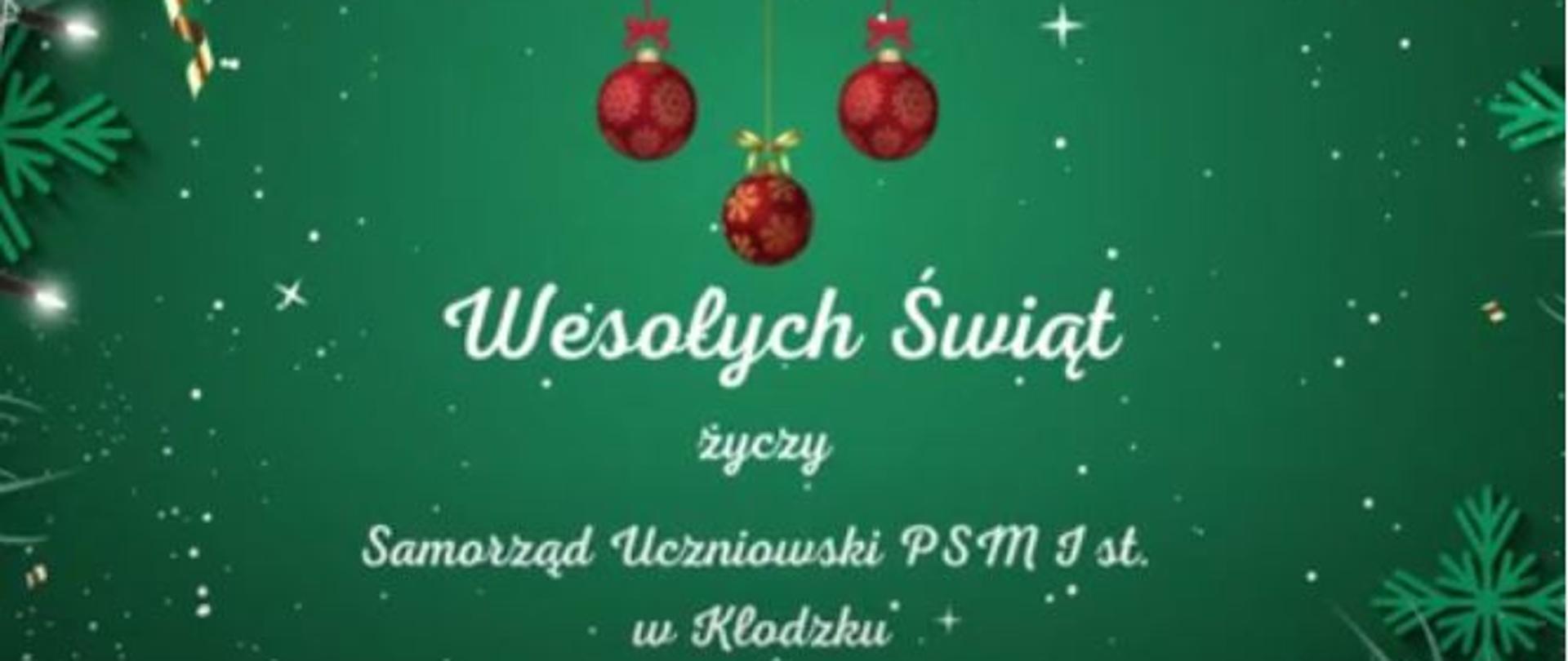 Plakat na zielonym tle, z grafika wiszących czerwonych bombek z tekstem "Wesołych Świąt życzy Samorząd Uczniowski PSM I st. w Kłodzku"