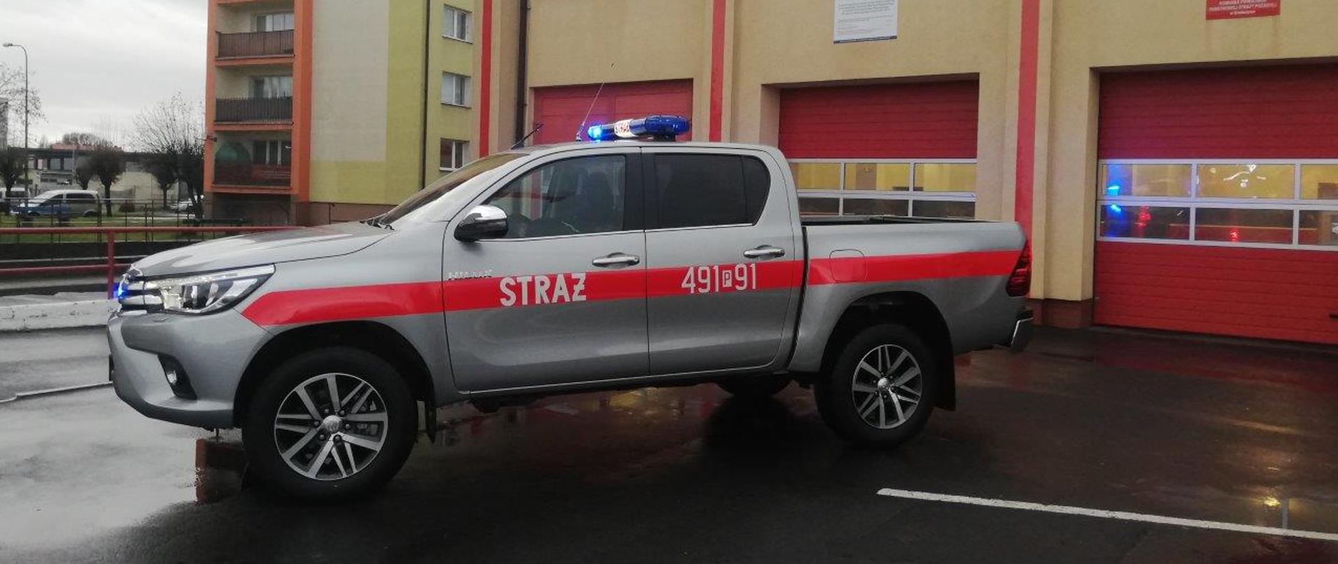 Bok pojazdu specjalnego marki Toyota Hilux. Widoczne numery operacyjne samochodu, który znajdzie się na wyposażeniu krotoszyńskich strażaków. Samochód posiada nadwozie terenowe z napędem 4x4, skrzynię ładunkową oraz przedział osobowy.