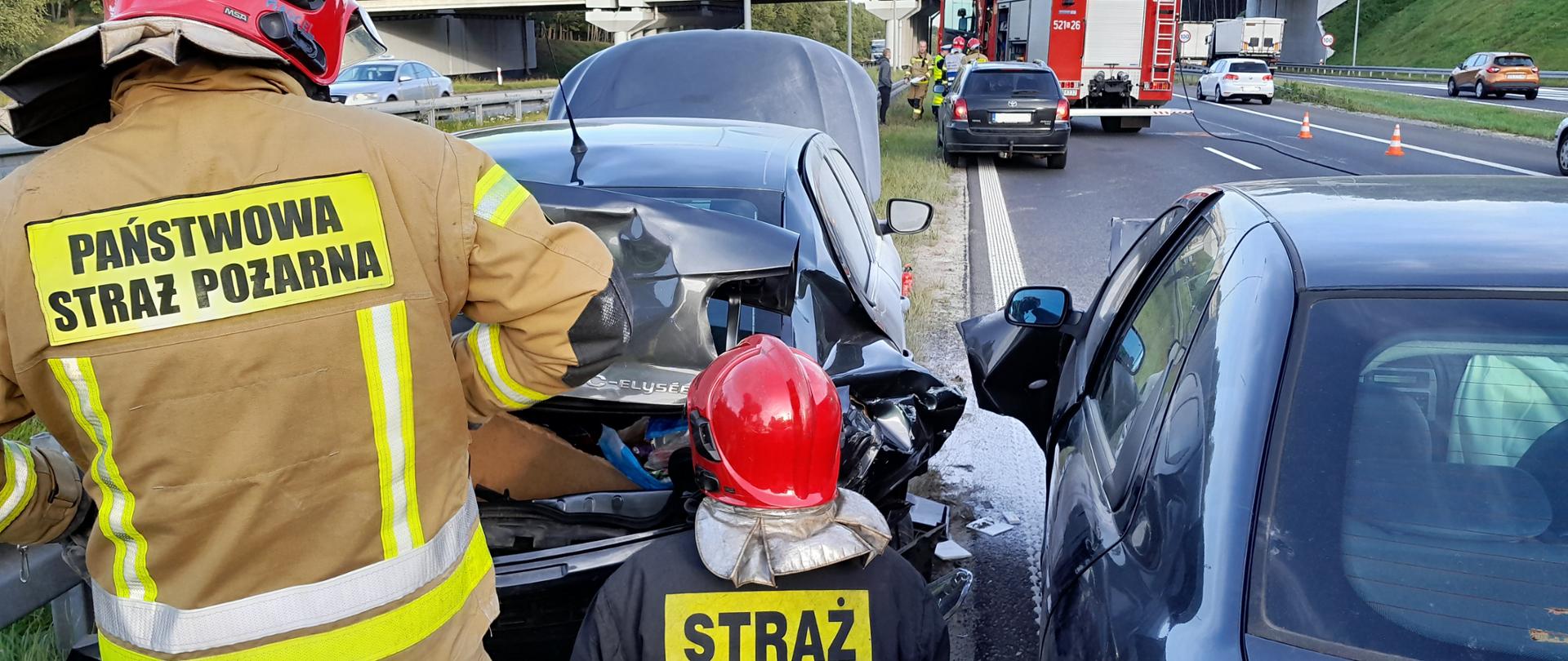 Strażacy zabezpieczający zbiornik gazu w uszkodzonym samochodzie