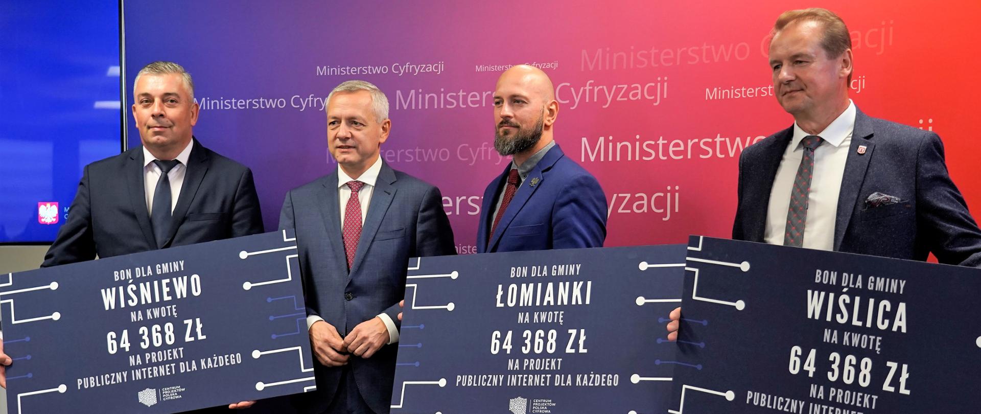 Czterech mężczyzn pozuje do wspólnego zdjęcia. W dłoniach trzymają 