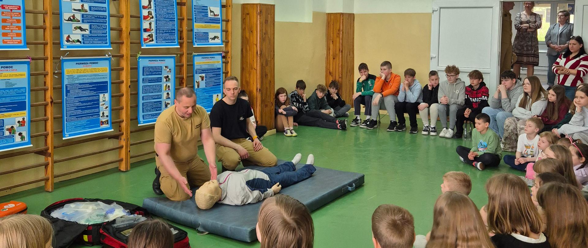 Dzieci przyglądające się pokazowi pierwszej pomocy przedmedycznej