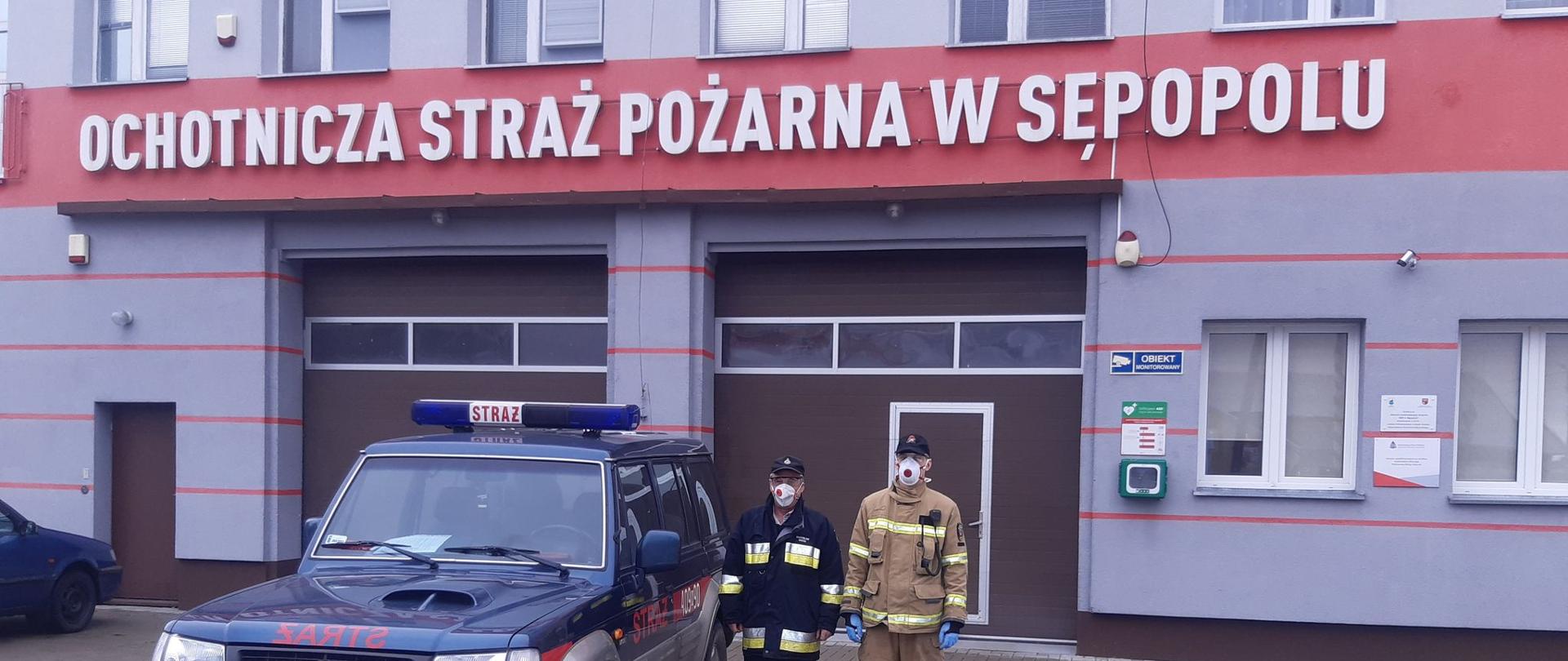 Na zdjęciu widać samochód i dwóch strażaków z Ochotniczej Straży Pożarnej w Sępopolu przygotowanych do transportu osób na szczepienia