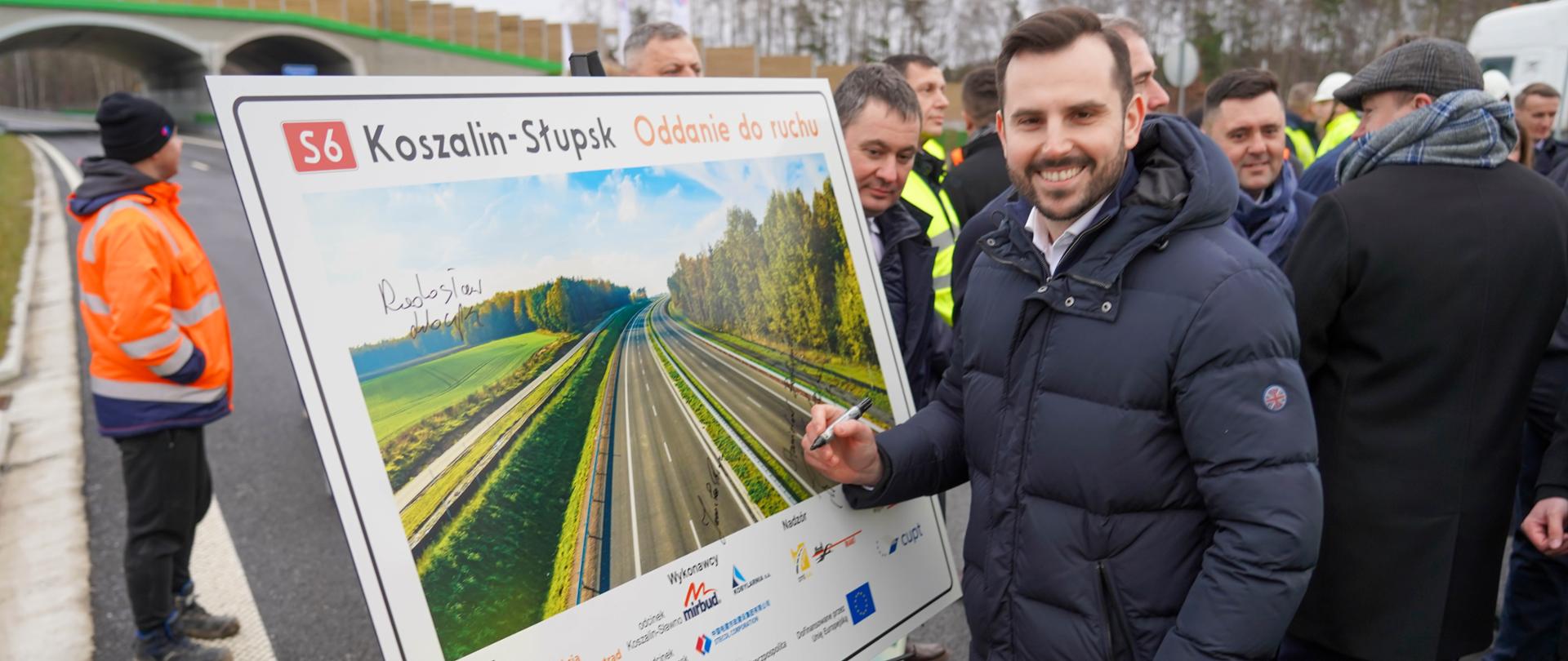 wicewojewoda Bartosz Brożyński podpisuje tablicę pamiątkową z otwarcia odcinka S6 Koszalin - Słupsk