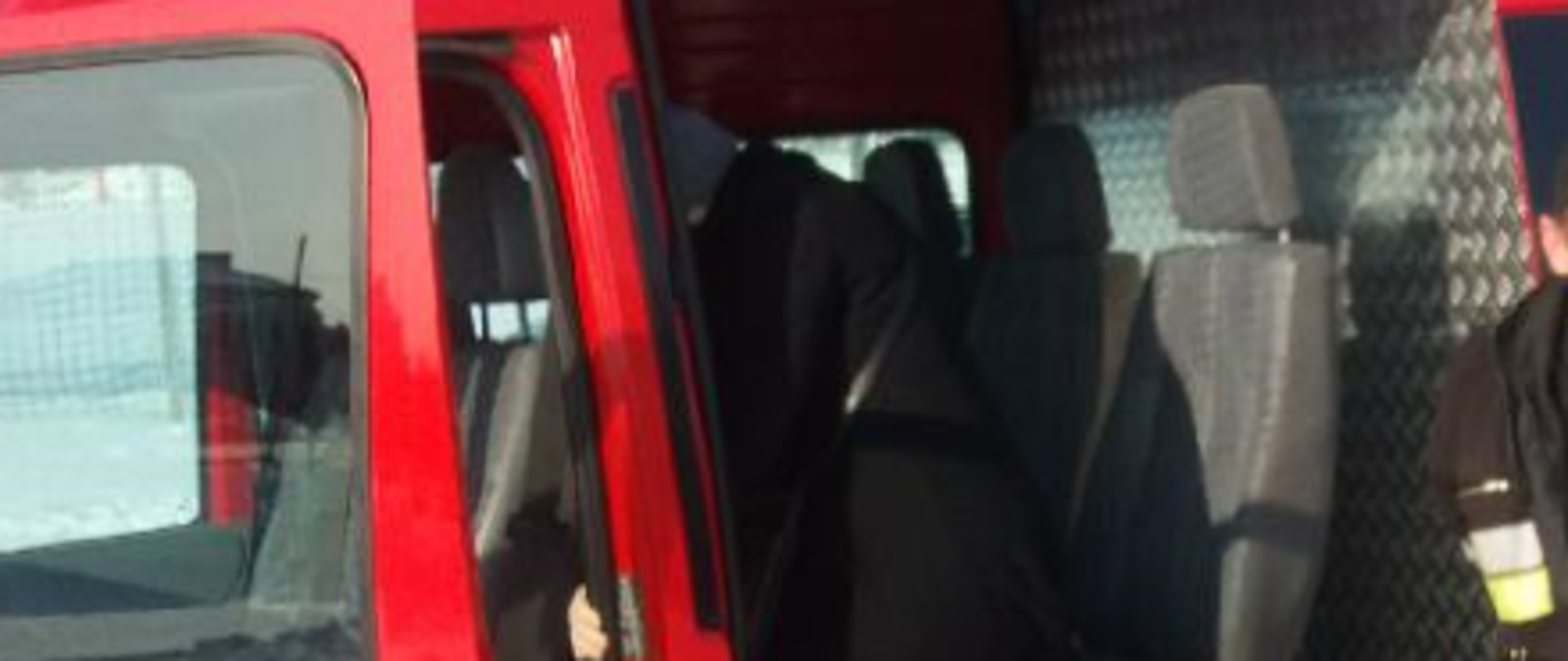 Na zdjęciu widać samochód pożarniczy typu bus do którego wsiada kobieta. Tuż za nią znajduje się strażak.