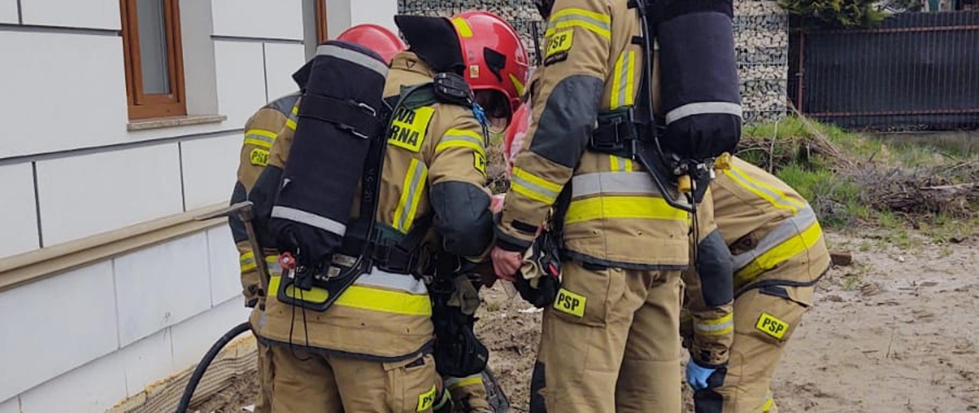 Strażacy prowadza działania przy studzience kanalizacyjnej 