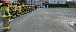 Zdjęcie ukazuje strażaków dwóch zmian służbowych podczas uroczystej zbiórki na placu komendy 