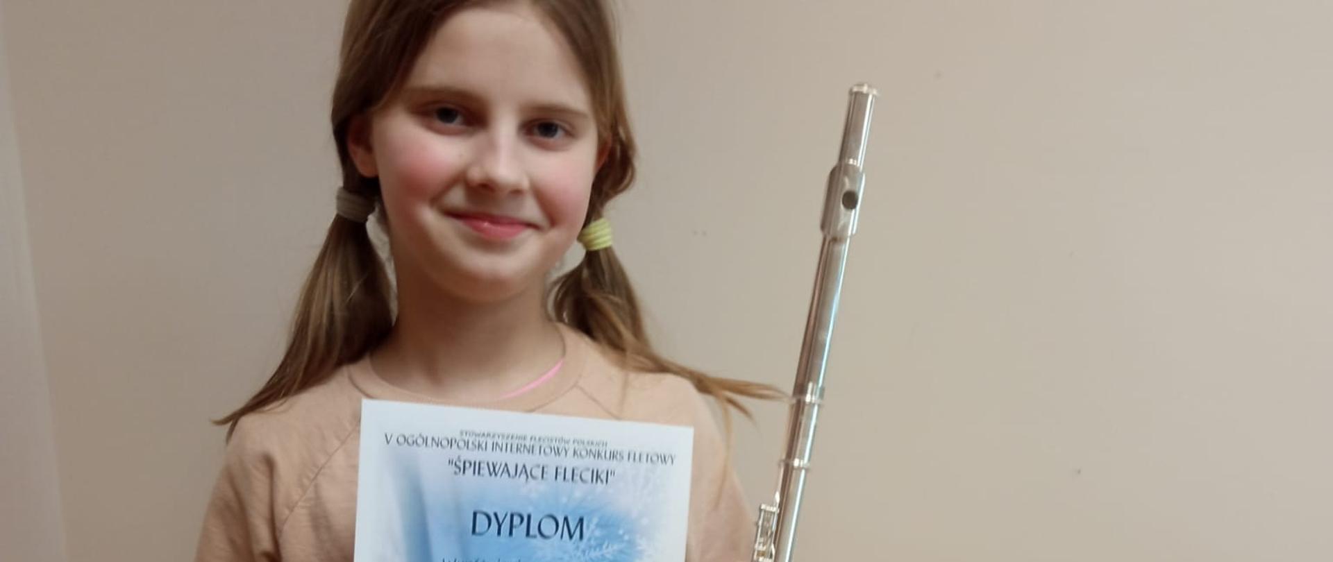 Dziewczynka trzyma dyplom i flet