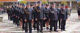 Strażacy PSP oraz druhowie OSP w umundurowaniu galowym stoją w szeregach na placu podczas uroczystego apelu.