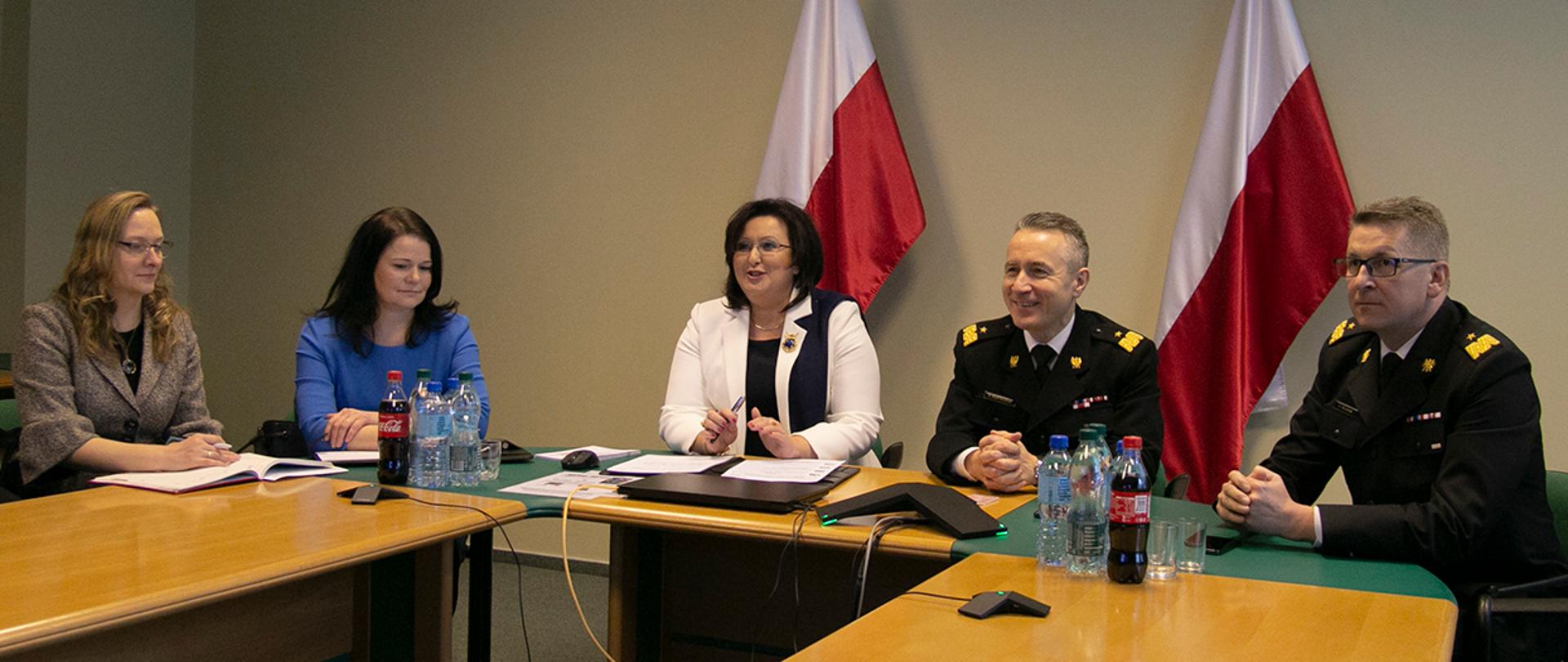 Osoby uczestniczące w wideokonferencji. Komendanci PSP i przedstawicielki ZER. W tle dwie biało-czerwone flagi
