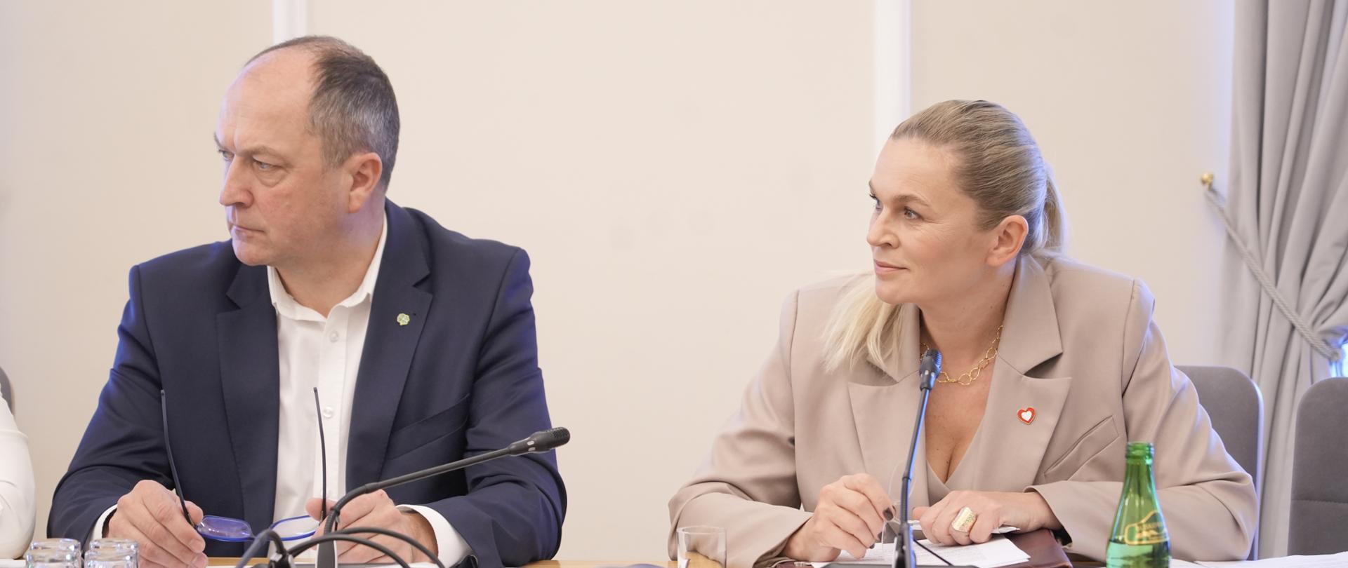 Widok na siedzących za stołem Minister Barbarę Nowacką i wiceministra Henryka Kiepurę, przed nimi ustawione mikrofony 