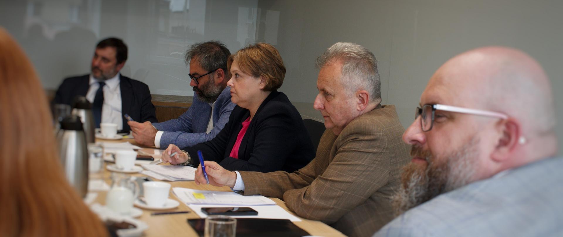 Zdjęcie z boku, za stołem siedzi kilka osób, pośrodku wiceminister Zioło-Pużuk.