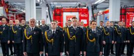 Na zdjęciu widoczni na pierwszym planie oficerowie odbierający awanse na wyższe stopnie służbowe z tle pododdział i czerwone samochody pożarnicze podczas apelu z okazji Dnia Strażaka 2025 w Komendzie Powiatowej Państwowej Straży Pożarnej w Gorlicach