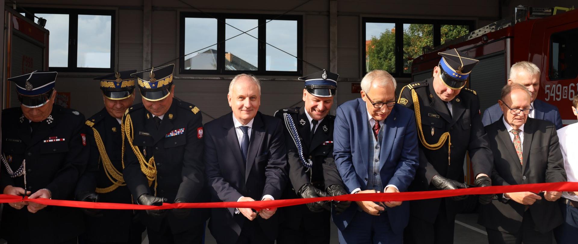 9 osób przecina czerwoną wstęgę - Wojewoda Pomorski, poseł Smoliński, Pomorski Komendant Wojewódzki, Wiceprezes ZOSP woj. pomorskiego, Komendant Powiatowy, Naczelnik i Prezes OSP, władze gminy