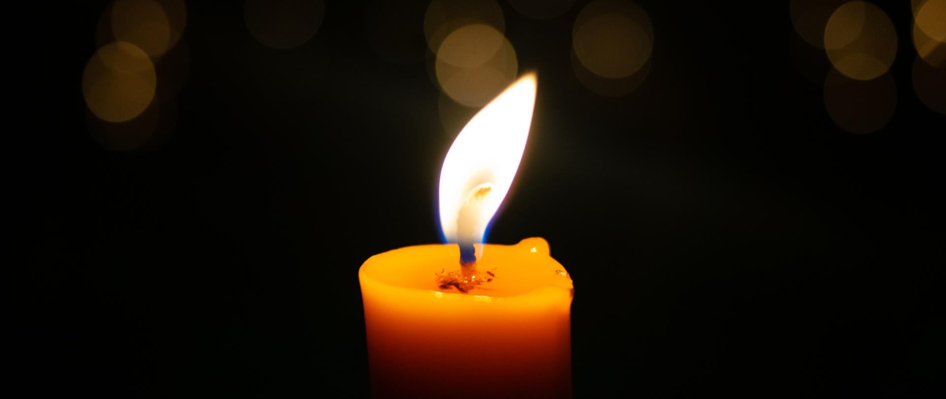 Płonąca świeca na ciemnym tle