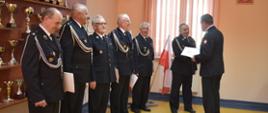 Komendant powiatowy Państwowej Straży Pożarnej w Pińczowie bryg. Grzegorz Karwat wręcza decyzję o przyznaniu świadczenia ratowniczego druhowi OSP