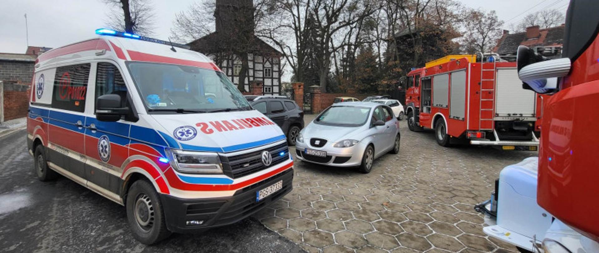 Karetka oraz zastępy straży stoją na placu przy kościele.