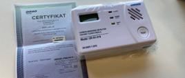 Detektor tlenku węgla zapakowany w foliowy woreczek, obok certyfikat - dokument potwierdzający poprawność działania sensora. 