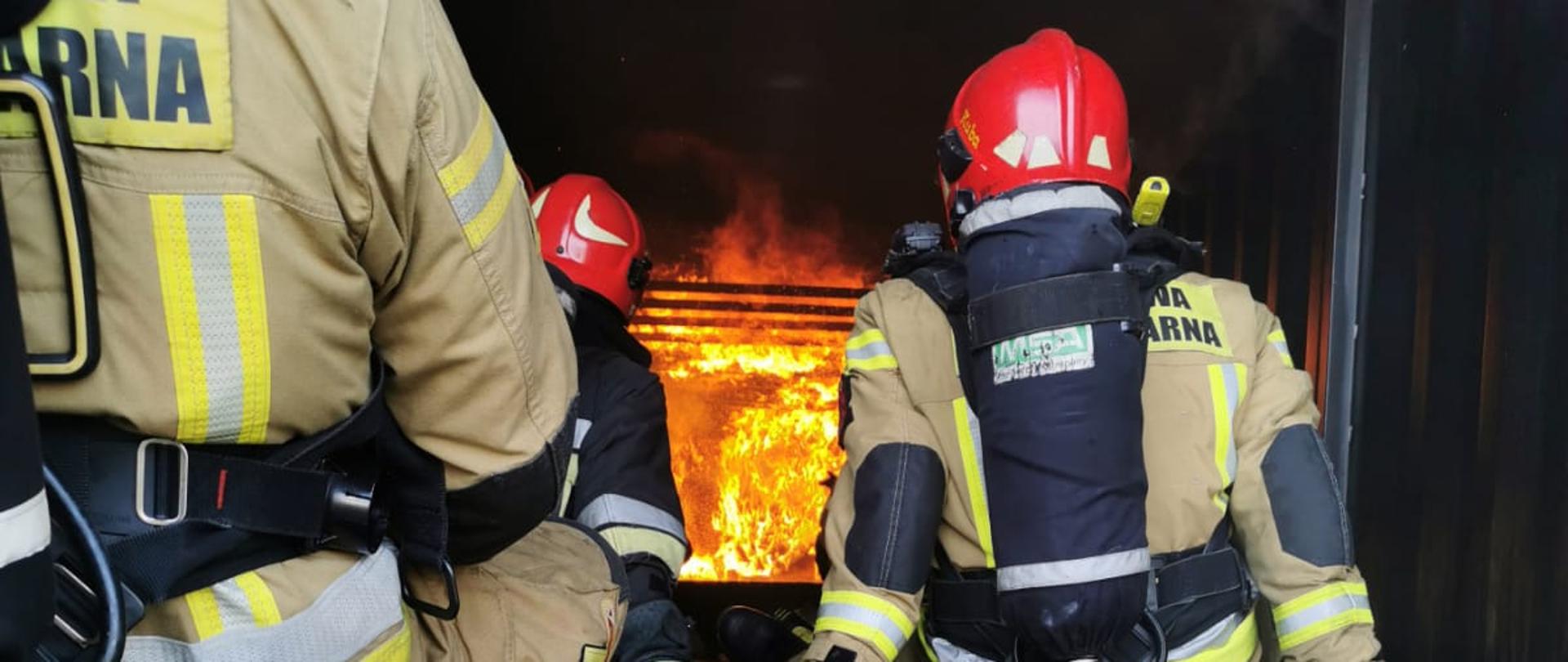 dwóch strażkaów siedzi w kontenerze w którycm się pali