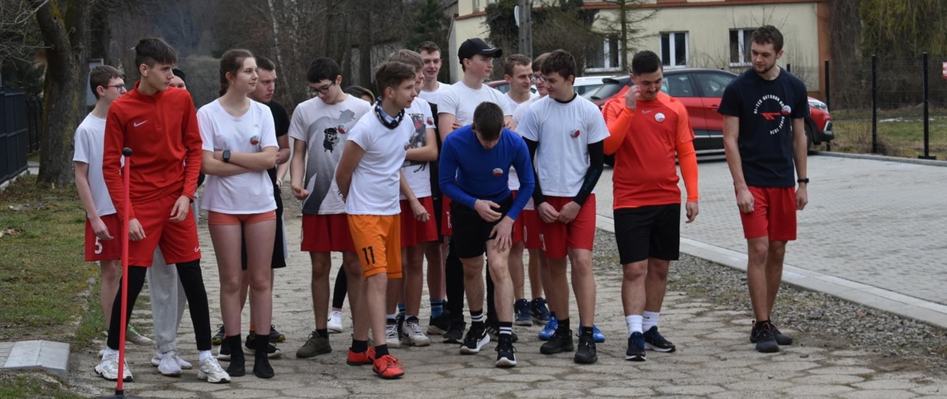 Zawodnicy ustawieni na starcie biegu na uliczce przy domach.