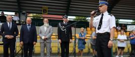 komendant powiatowy mł bryg Arkadiusz Makowski ubrany w strój galowy wita zebranych gości przez mikrofon w tle ustawieni są przedstawiciele władz lokalnych