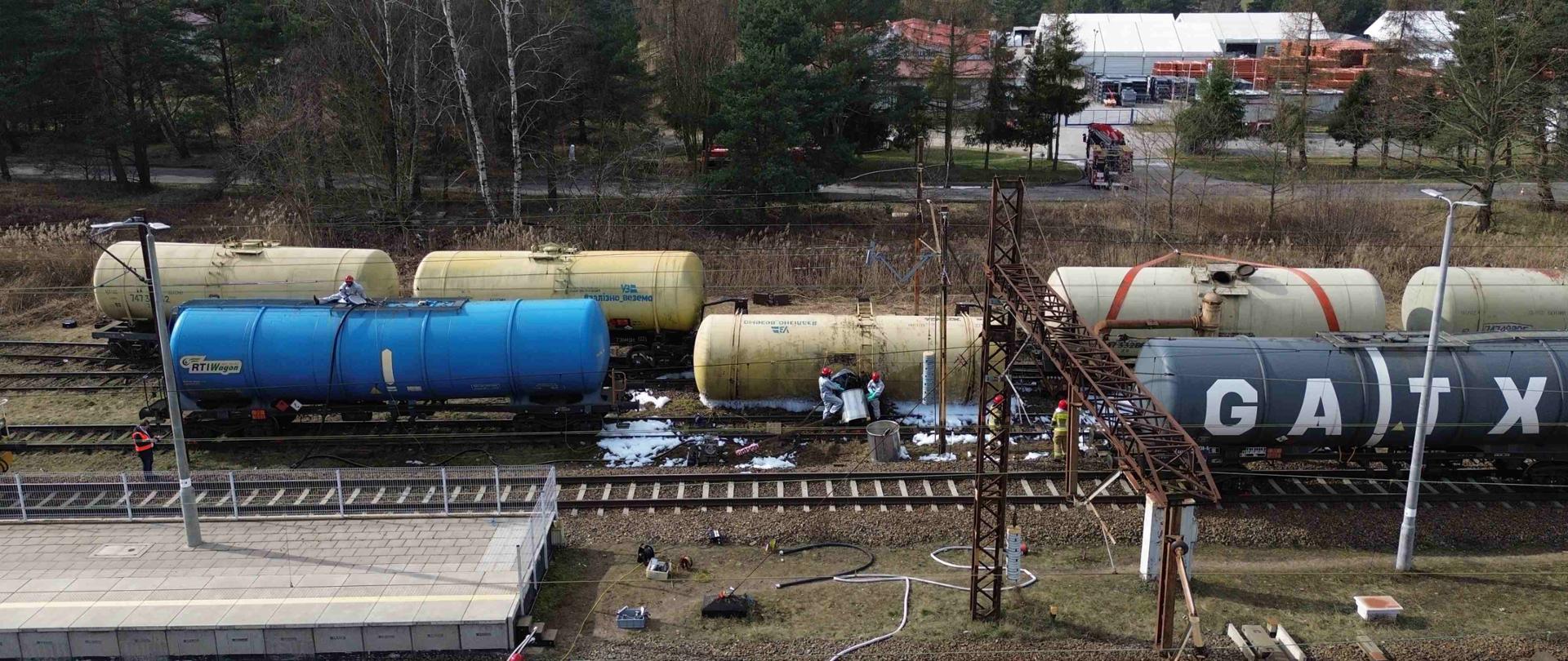 Na zdjęciu widać przewrócone cysterny kolejowe na stacji kolejowej. 