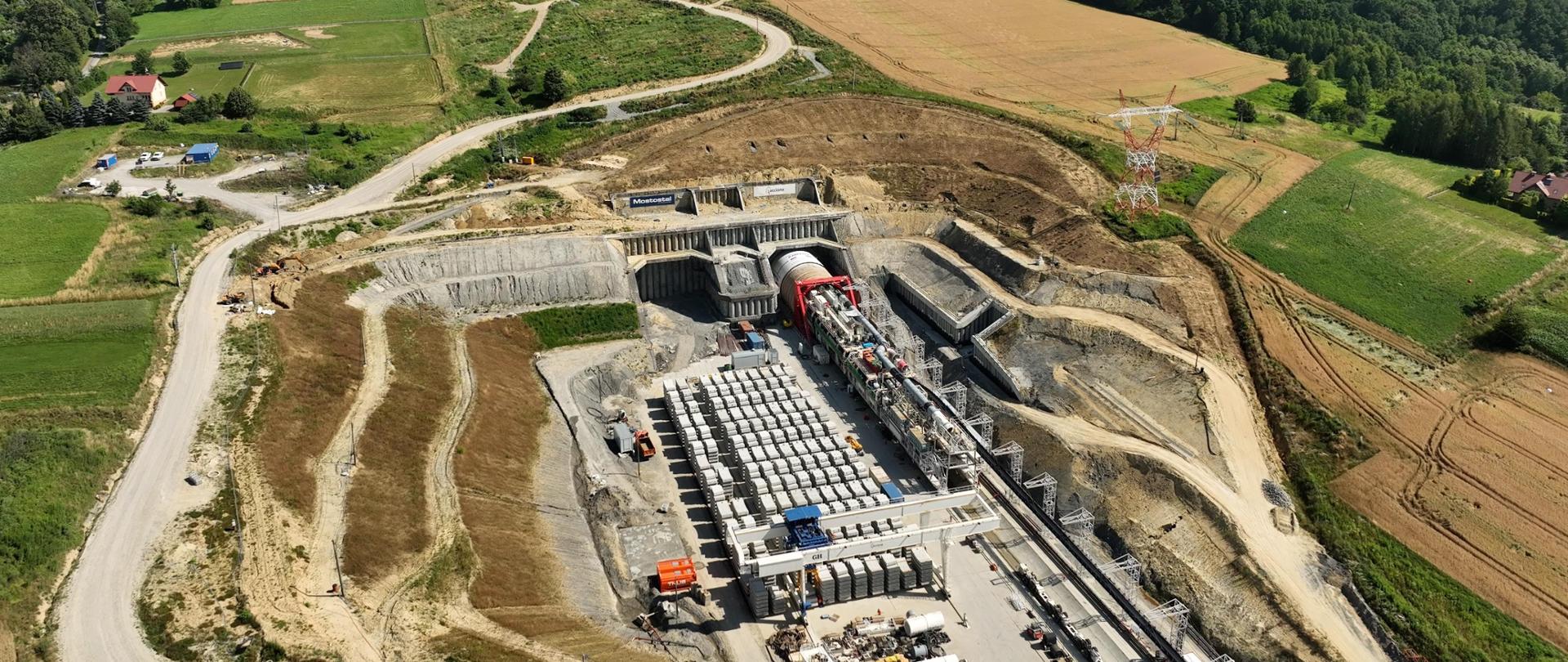 Widok z góry na odcinek drogi ekspresowej S19 Rzeszów Południe - Babica i portal południowy. Widać wzgórze, do którego dosunięta jest maszyna TBM, która będzie drążyć tunel. 