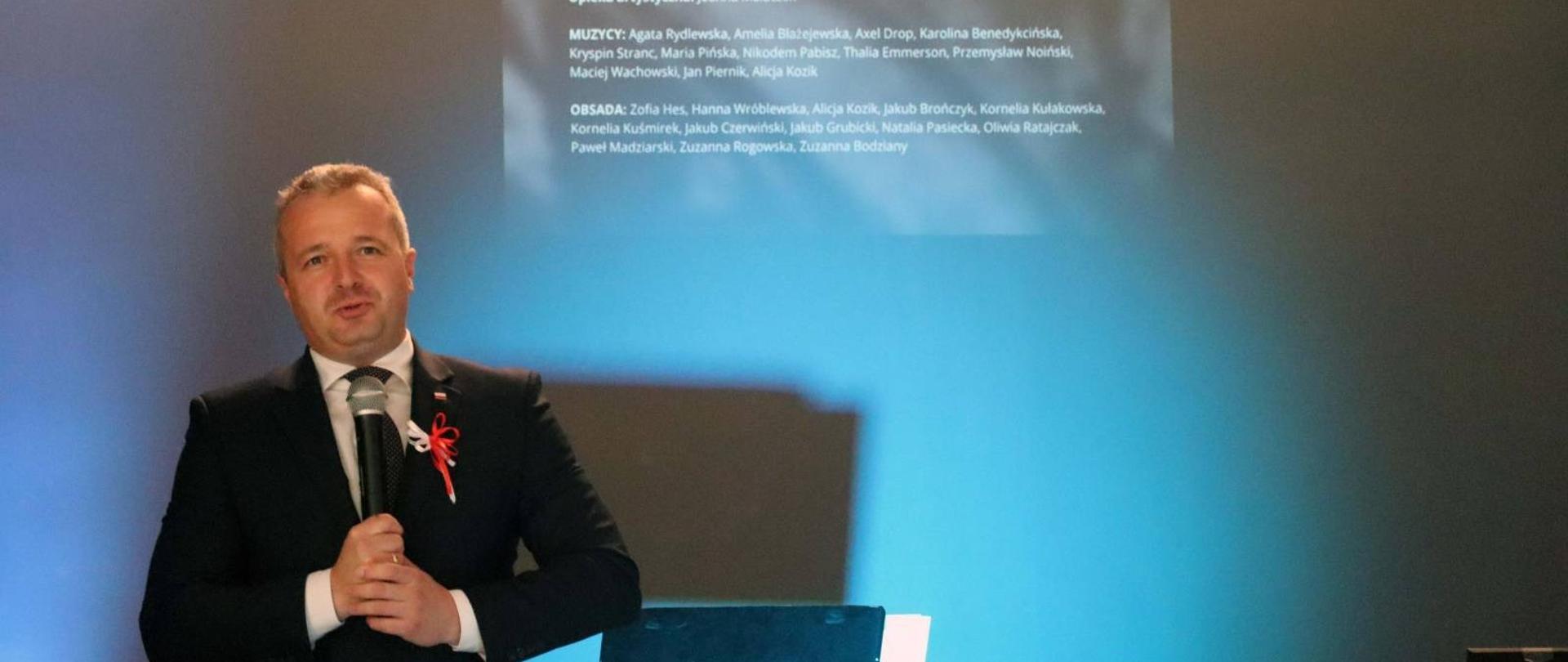 Jeden mężczyzna stojący z mikrofonem i wypowiadający się