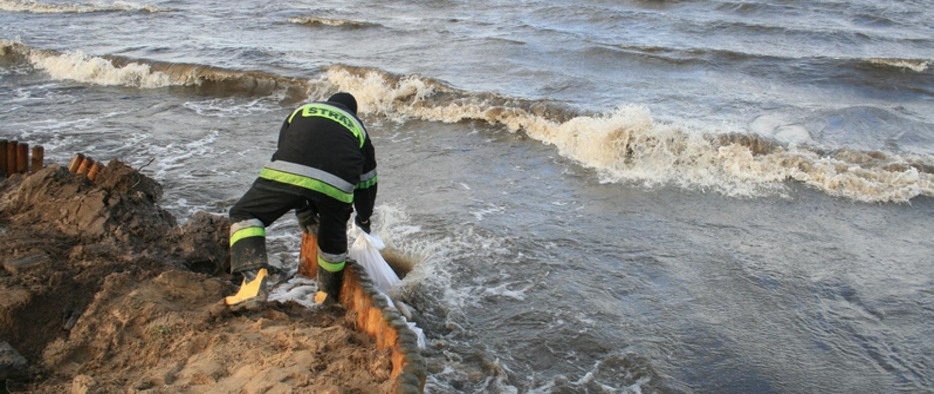 Zdjęcie przedstawia strażaka nad wodą