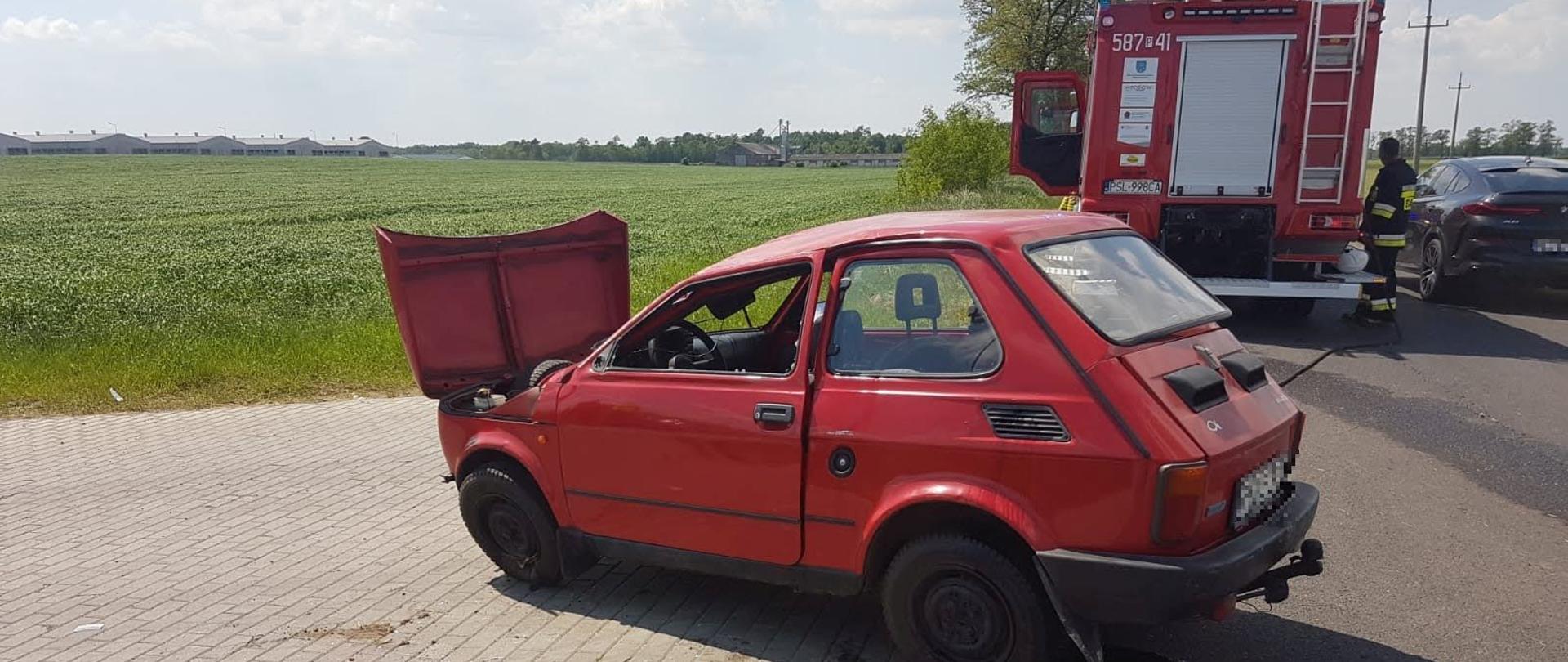 samochód po dachowaniu w tle samochód strażacki oraz strażak 