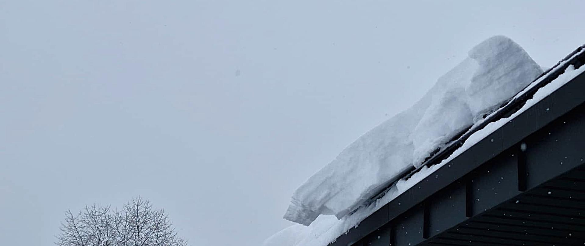 Na dachu budynku znajduje się duży nawis śniegu. Okucia dachu w kolorze czarnym .