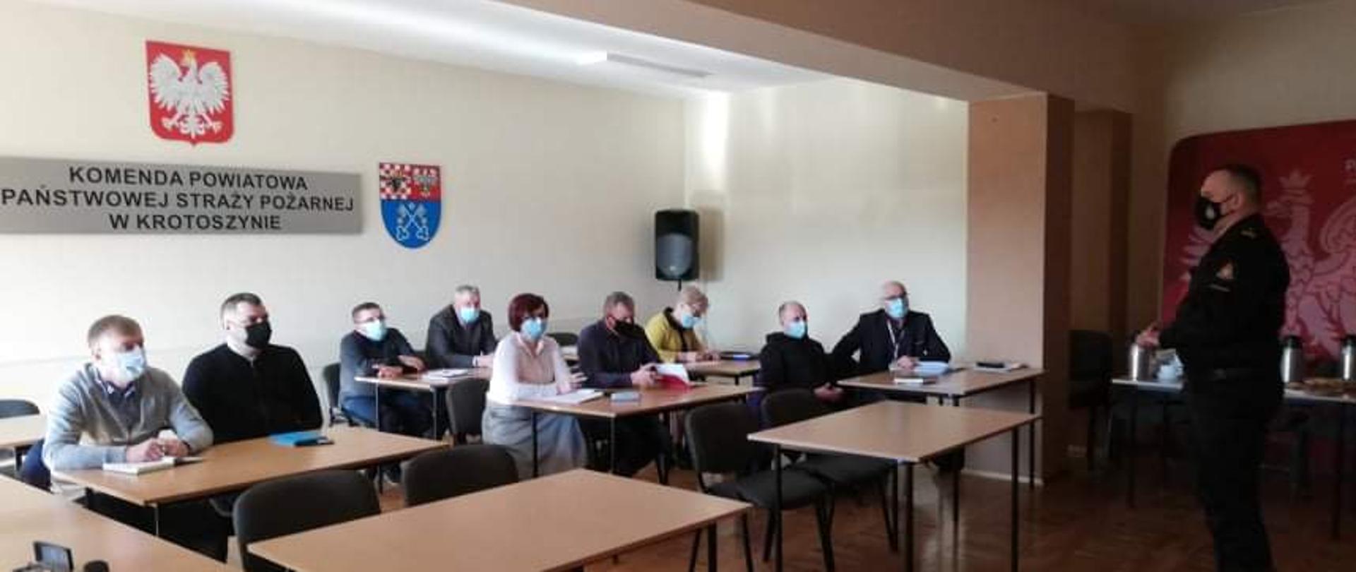Na świetlicy komendy powiatowej PSP w Krotoszynie, komendant powiatowy wita zaproszonych gości. Spotkanie zostało zorganizowane celem omówienia rozporządzenia dotyczącego świadczenia ratowniczego dla ratowników OSP. Uczestnicy w osobach przedstawicieli samorządów terytorialnych oraz komendantów miejsko - gminnych Z OSP RP zachowują zasady reżimu sanitarnego korzystając z maseczek ochronnych, 