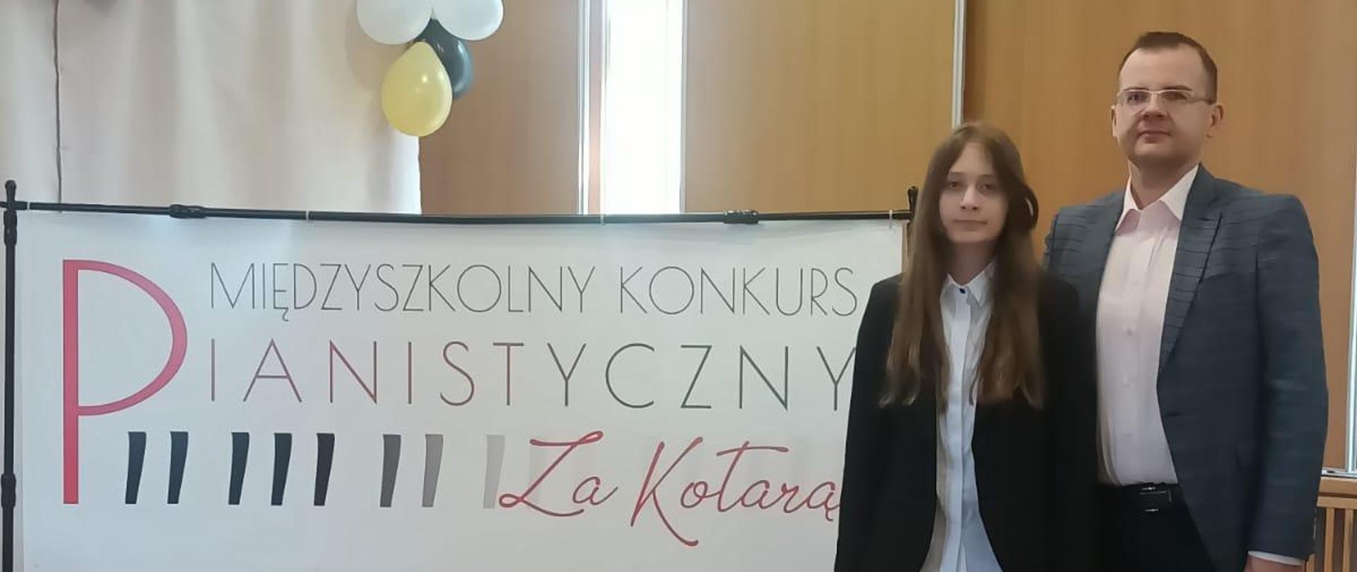 Zdjęcie przedstawia uczennicę V kl. C.6 naszej szkoły Karolinę Podporę wraz z nauczycielem Grzegorzem Derubą. W tle widać baner konkursowy