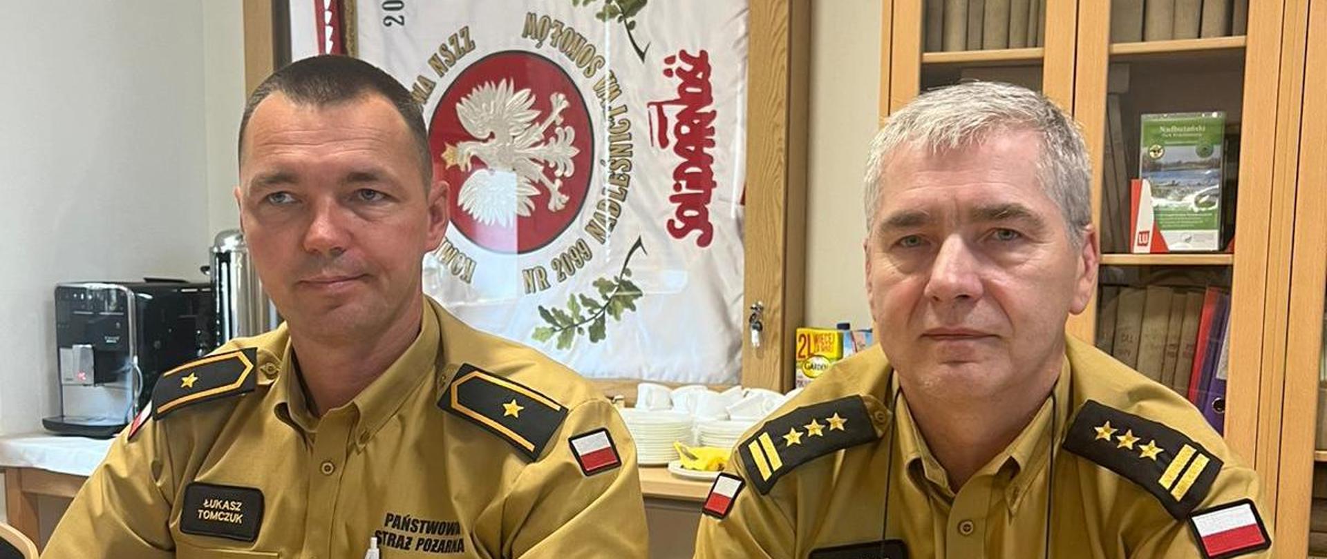 Posiedzenie Komisji Założeń projektu Planu Urządzania Lasu dla Nadleśnictwa Sokołów na lata 2026 – 2035. - na zdjęciu 2 strażaków w ubraniu służbowym siedzi w pomieszczeniu.