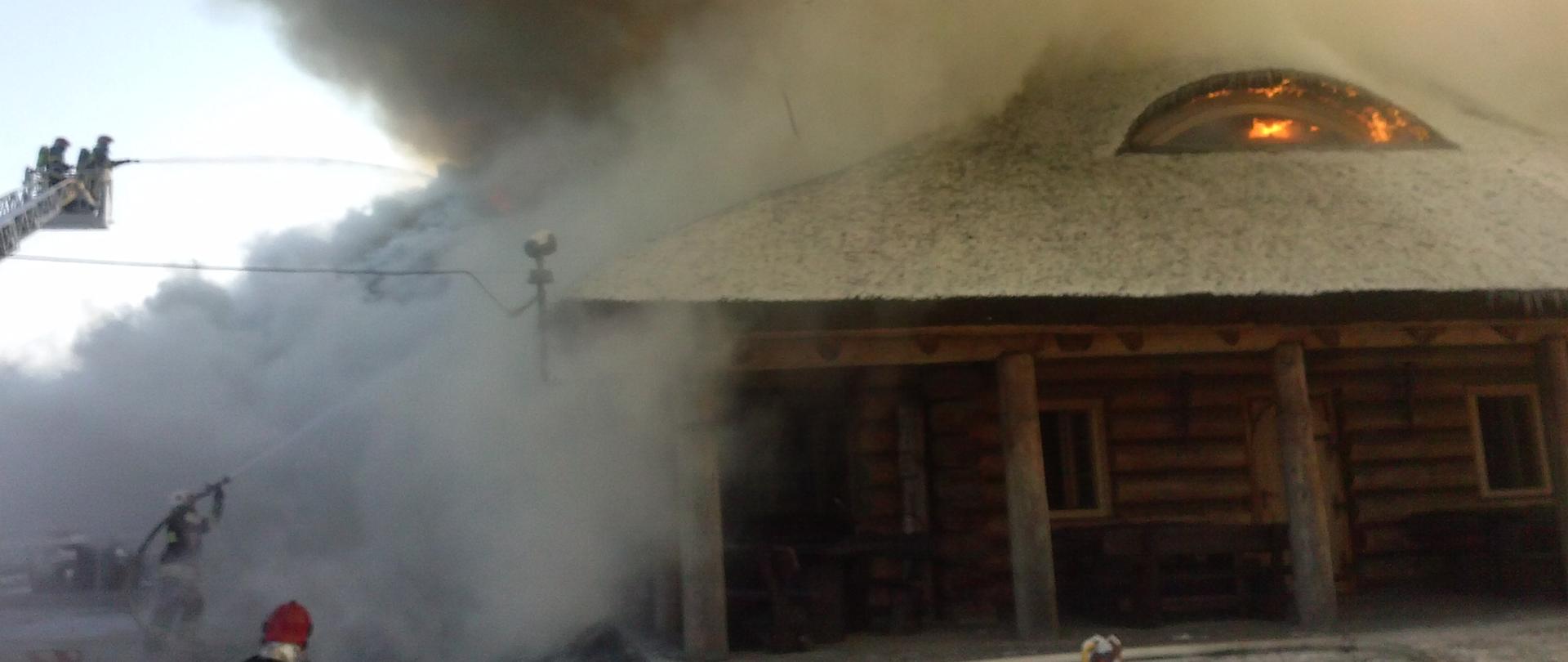 palący się dach drewnianego domu, dużo dymu