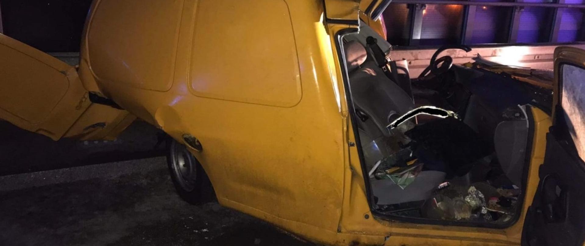 Zdjęcie obrazuje uszkodzony samochód osobowy Volswagen Caddy. Siła uderzenia zgniotła przód pojazdu w taki sposób, że podróżującym pozostało niewiele miejsca. W wyniku uderzenia w bariery energochłonne zgnieciony został również tył pojazdu. W tle widać bariery dźwiękochłonne.