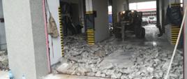 Fotografia przedstawiająca prace rozbiórkowe starej posadzki garażowej na którym widać maszynę do skuwania betonu krusząca starą posadzkę garażową.