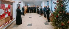 Zdjęcie przedstawia uczestników strażackiego spotkania opłatkowego (funkcjonariusze, pracownicy cywilni oraz zaproszeni goście) zgromadzonych w świetlicy Komendy Powiatowej Państwowej Straży Pożarnej w Gołdapi podczas składania wszystkim obecnym i Ich rodzinom życzeń z okazji Świąt Bożego Narodzenia oraz podziękowań za współpracę i wsparcie w mijającym roku przez Komendanta Powiatowego Państwowej Straży Pożarnej w Gołdapi st. bryg. Wojciecha Szczepanika