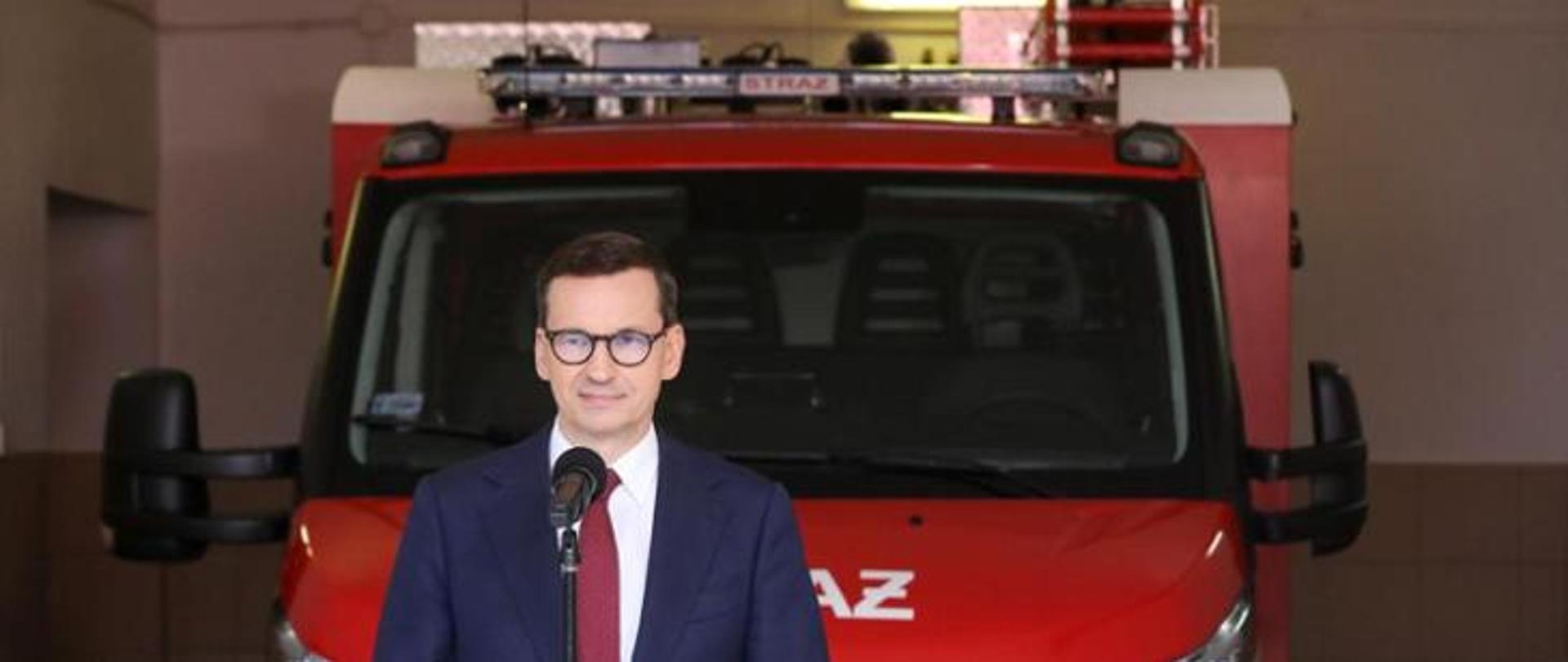 Premier Mateusz Morawiecki na pierwszym planie w tle wóz strażacki należący do OSP Zendek